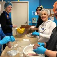 Alumni prepare meat together at Kids' Food Basket.